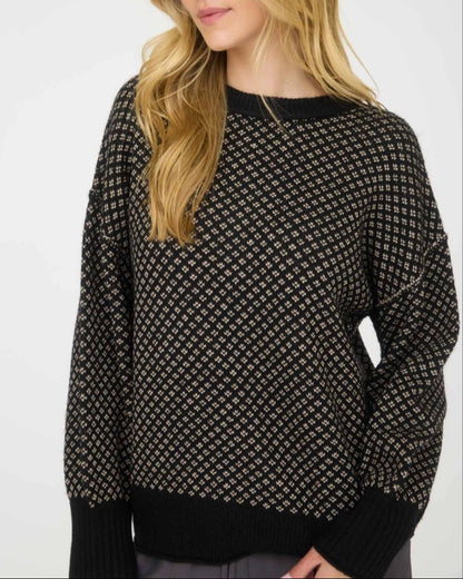 Woman wearing a black patterned sweater against a white background.