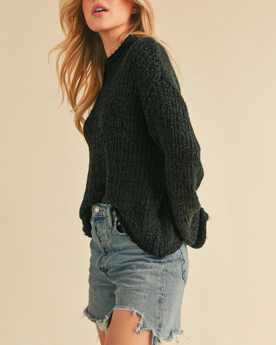 Woman wearing a mock neck black sweater with boxy relaxed fit. 