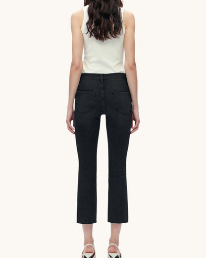 Person wearing a white sleeveless top and black pants on a white background.