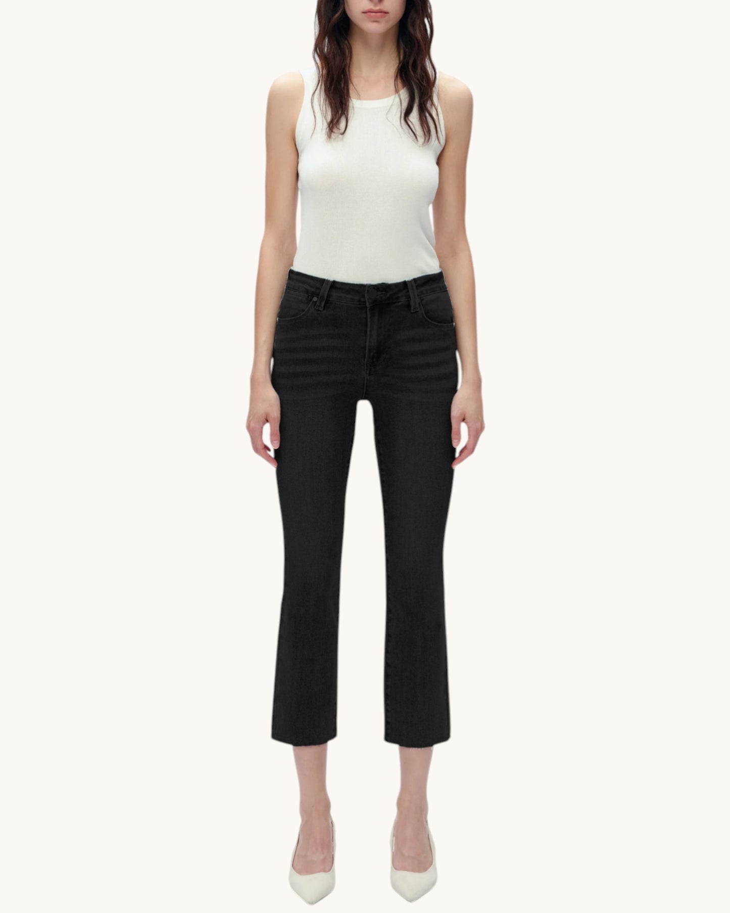 Person wearing black jeans and a white tank top on a white background.