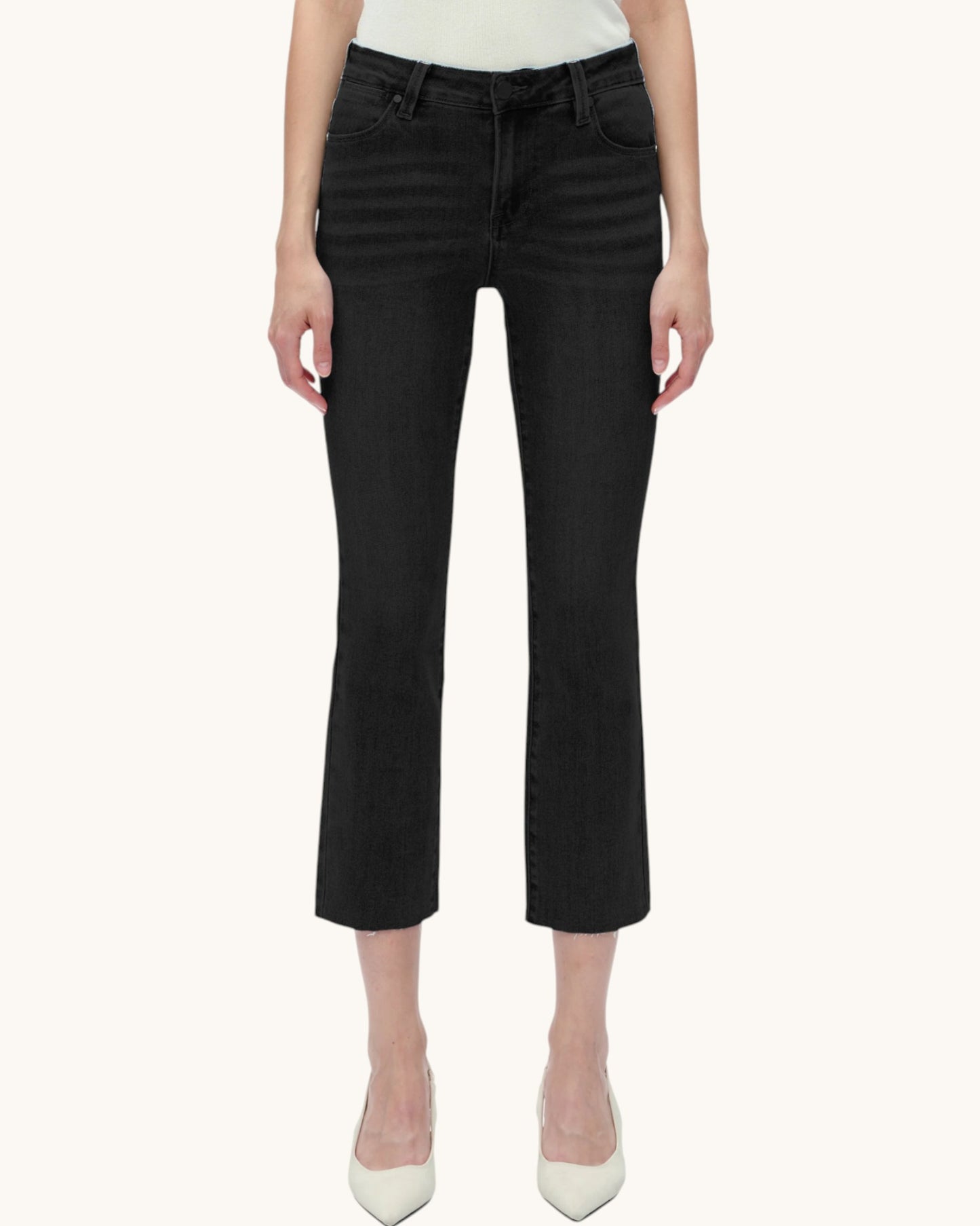 Person wearing black cropped jeans on a white background.