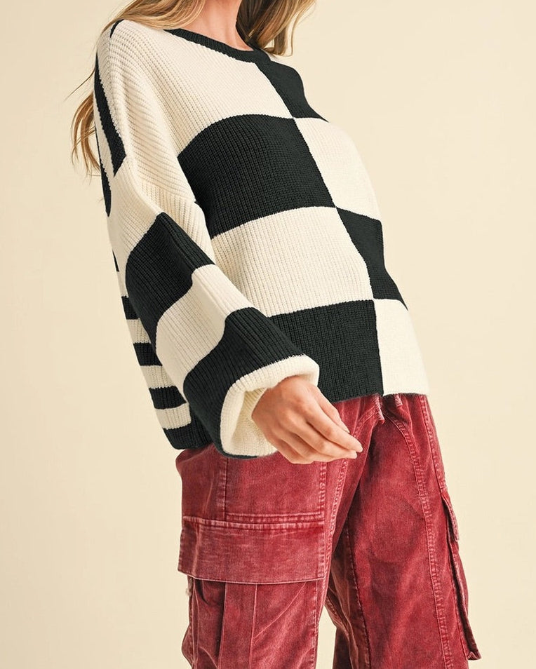 Woman wearing a black and white striped sweater and red pants on a beige background.