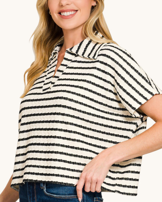 Woman wearing a black and white striped shirt with a light background.