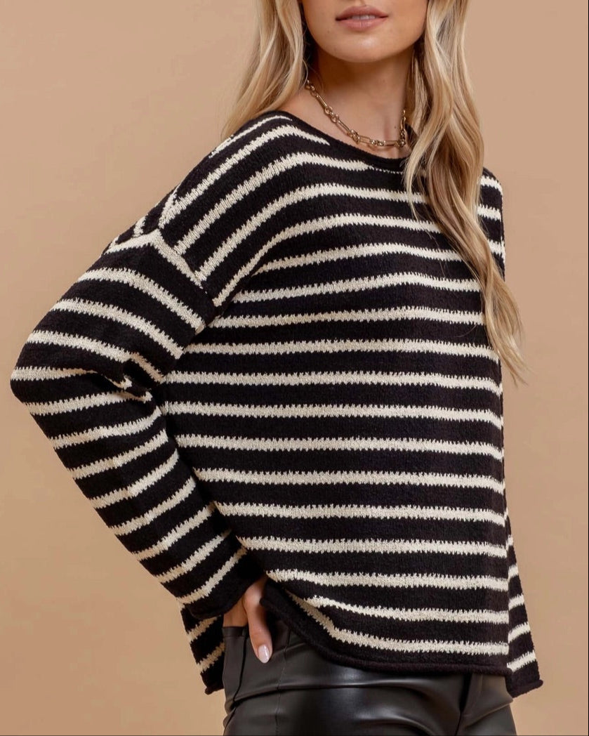 Woman wearing a black and white striped sweater against a beige background.