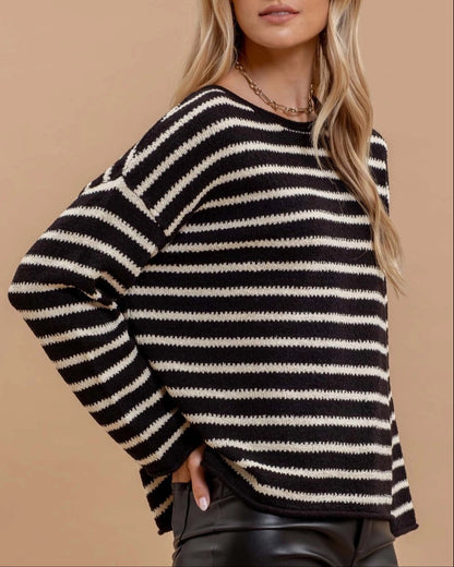 Woman wearing a black and white striped sweater against a beige background.