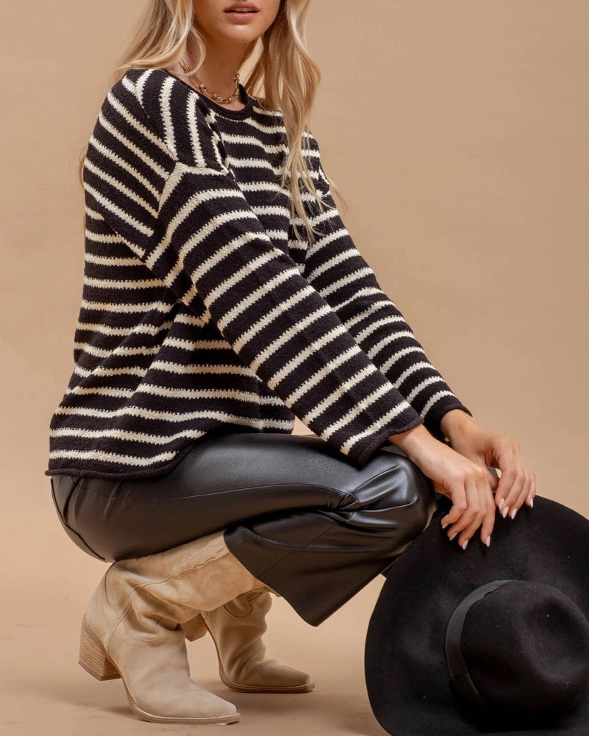 Woman wearing a black and white striped sweater with a beige background.