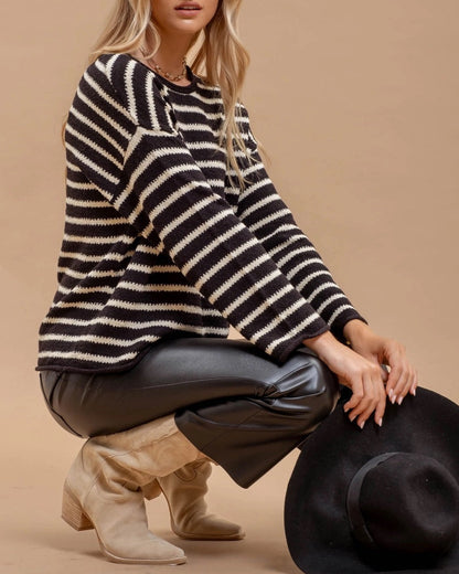 Woman wearing a black and white striped sweater with a beige background.