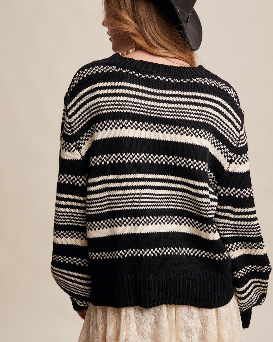 Woman wearing a Black and ivory Fair Isle inspired striped sweater with relaxed fit and ribbed trim.