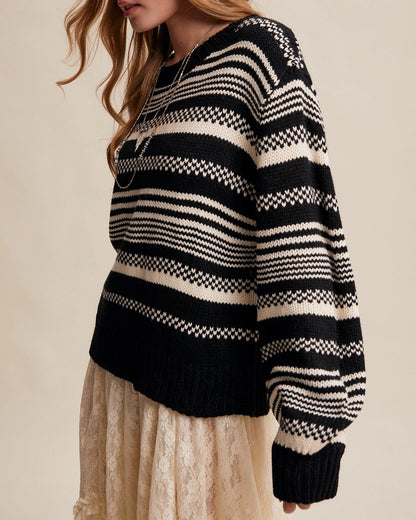 Woman wearing a Black and ivory Fair Isle inspired striped sweater with relaxed fit and ribbed trim.