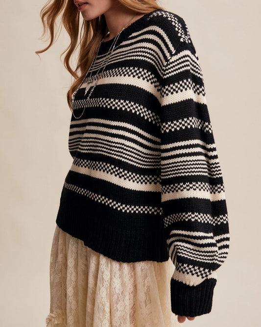 Woman wearing a Black and ivory Fair Isle inspired striped sweater with relaxed fit and ribbed trim.