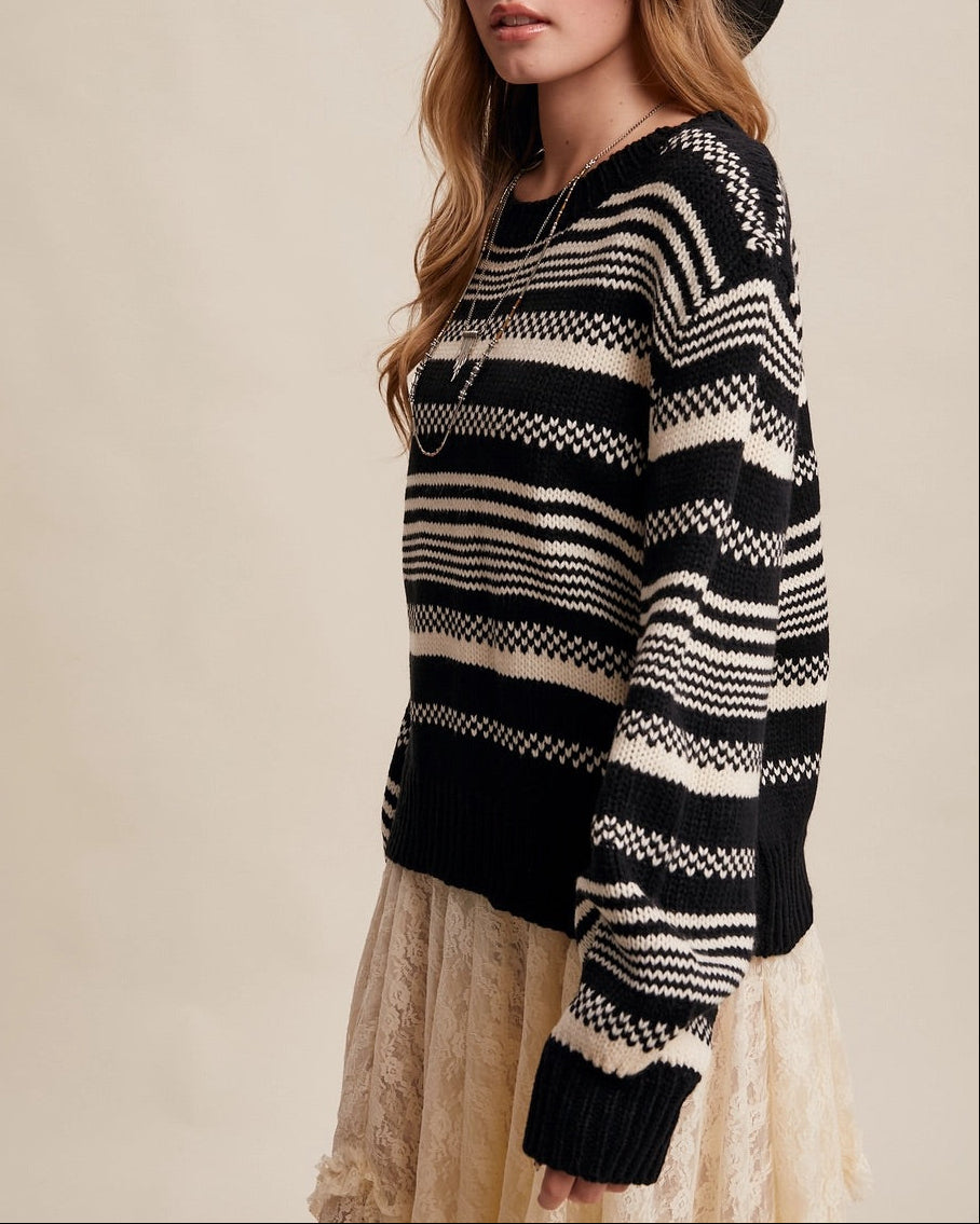 Woman wearing a Black and ivory Fair Isle inspired striped sweater with relaxed fit and ribbed trim.