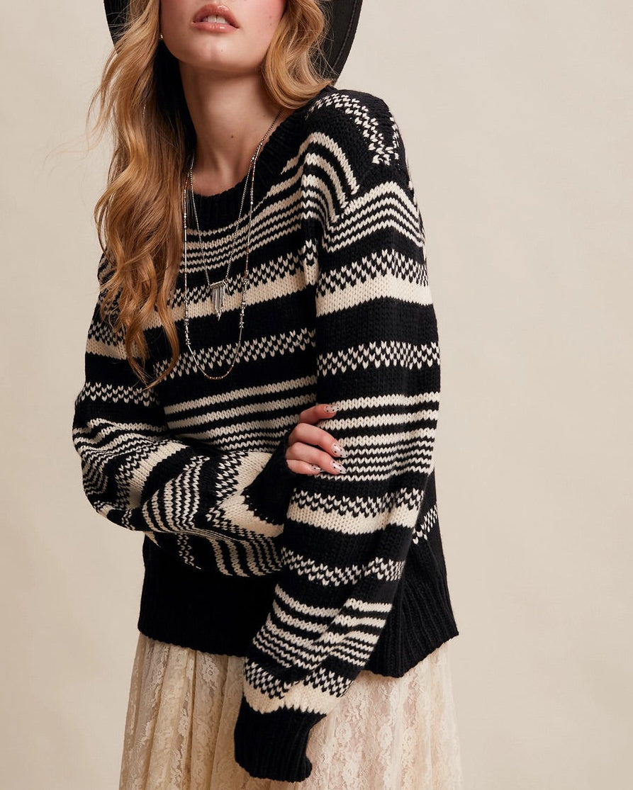 Woman wearing a Black and ivory Fair Isle inspired striped sweater with relaxed fit and ribbed trim.