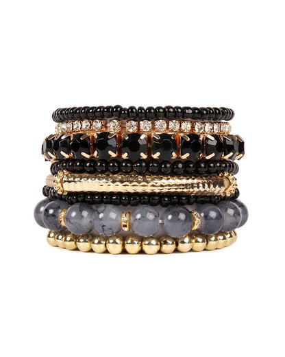 Stack of beaded bracelets with black, gold, and gray beads on a white background.