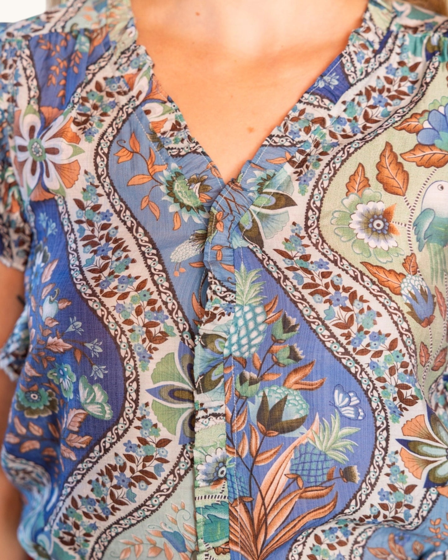 Close-up of a person wearing a colorful patterned shirt with floral and geometric designs.