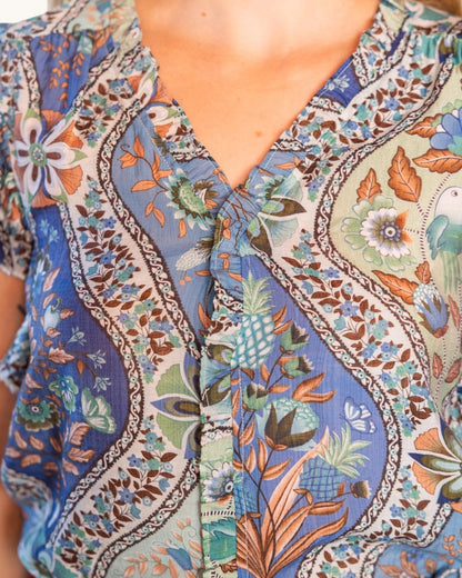 Close-up of a person wearing a colorful patterned shirt with floral and geometric designs.