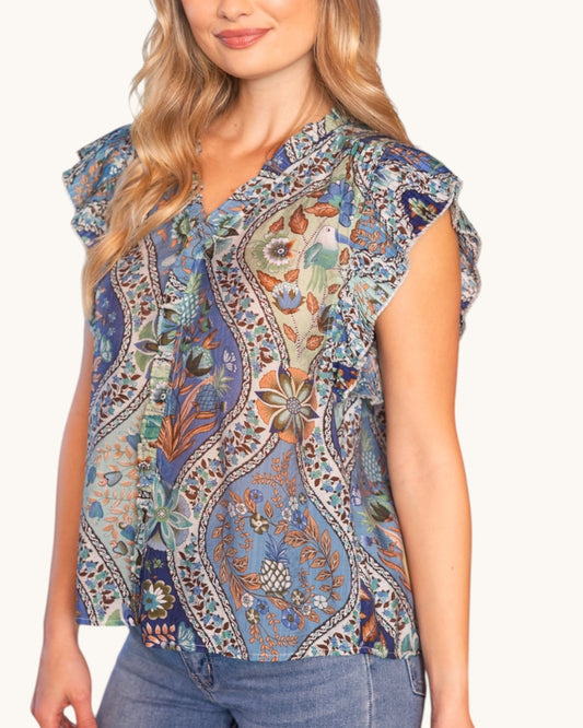 Woman wearing a sleeveless floral patterned top with jeans on a white background.