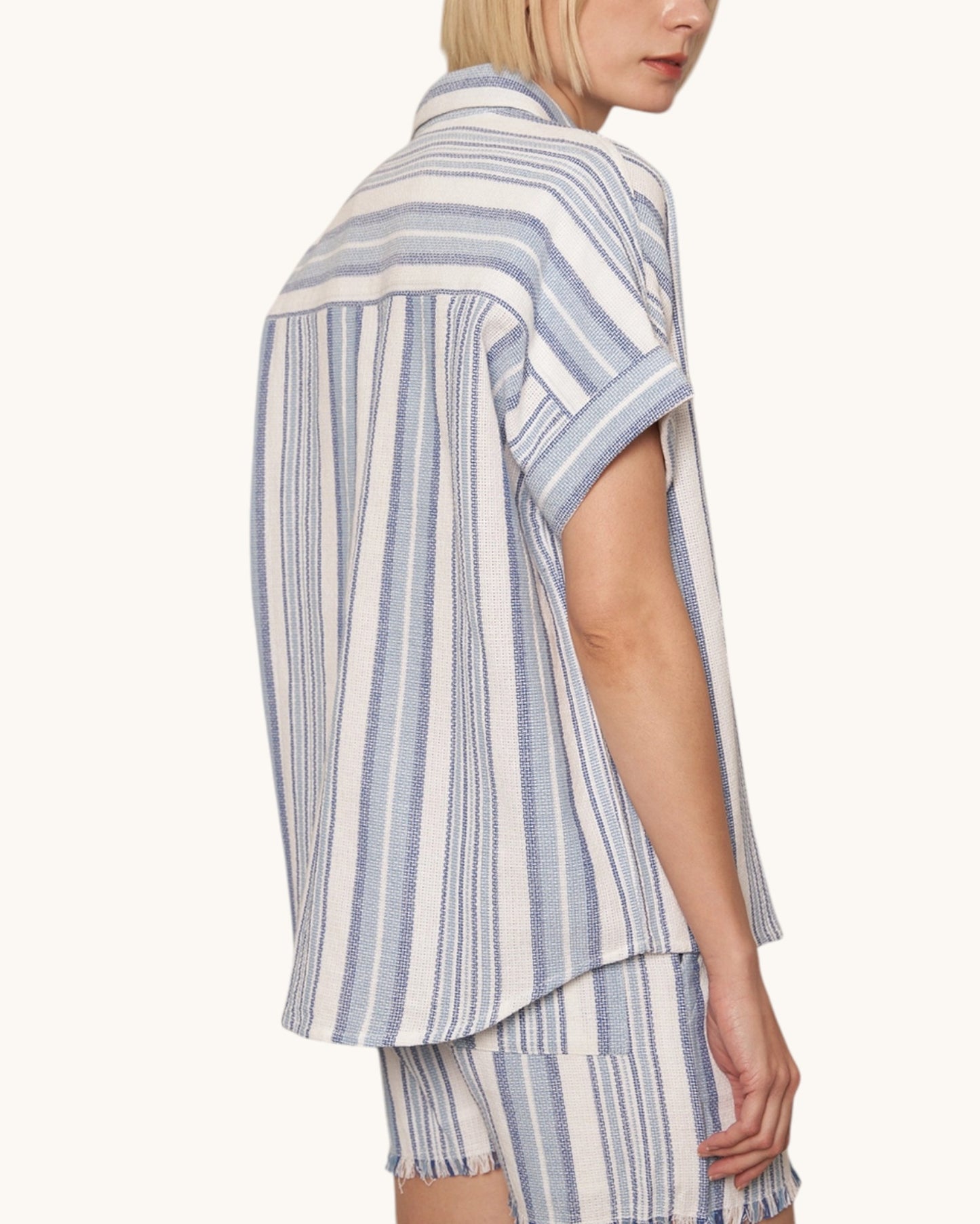 Side view of a person wearing a blue and white striped shirt and shorts on a white background.