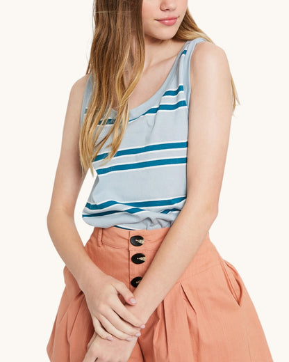 Woman wearing a striped tank top and orange pants on a white background.