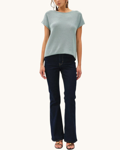 Woman wearing a light blue top and dark blue jeans on a white background.