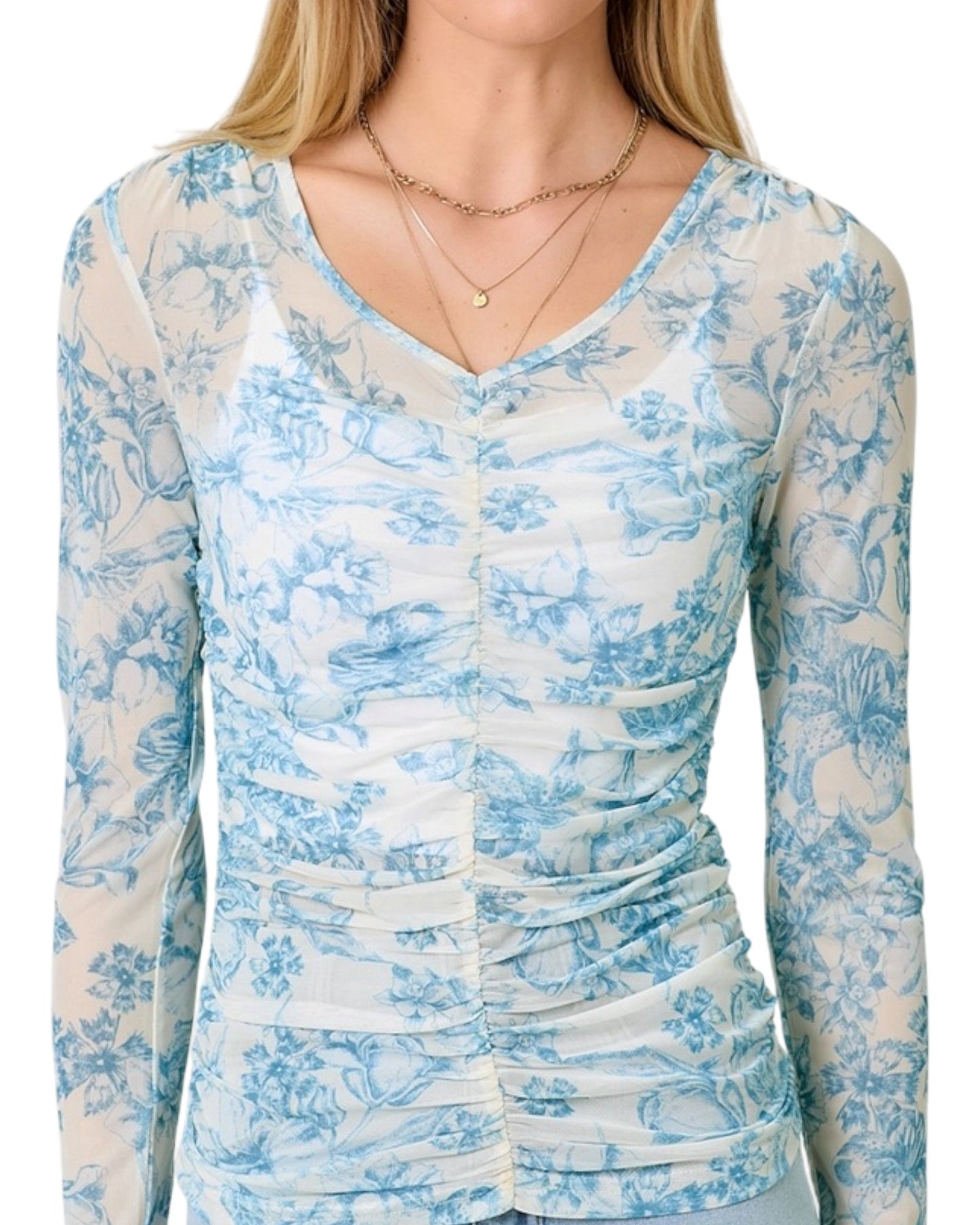 Woman wearing a white and blue floral long-sleeve top on a white background.