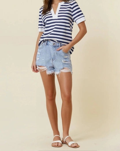 Woman wearing Navy and White striped knit V-neck short sleeve top with white trim and denim shorts. 