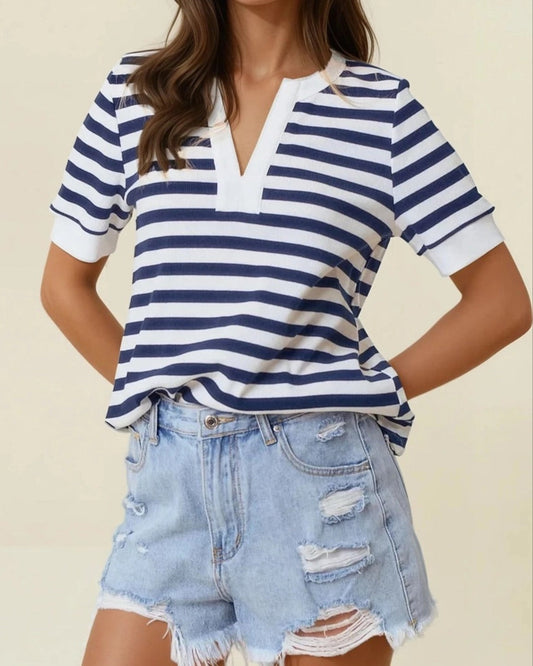 Woman wearing a striped shirt and denim shorts against a beige background.