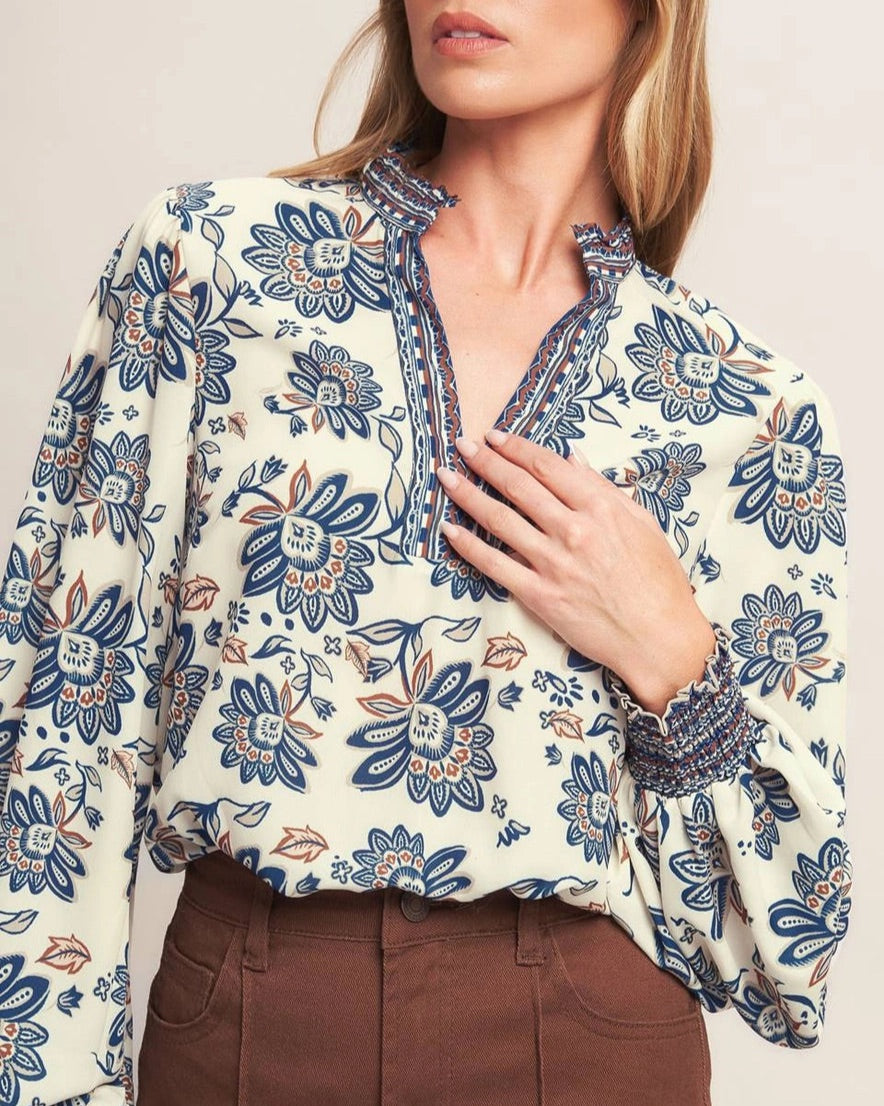 Ivory navy border print blouse with ruffled V neckline and smocked cuffs. 