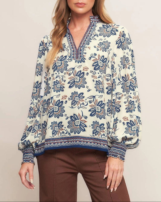 Ivory navy border print blouse with ruffled V neckline and smocked cuffs.