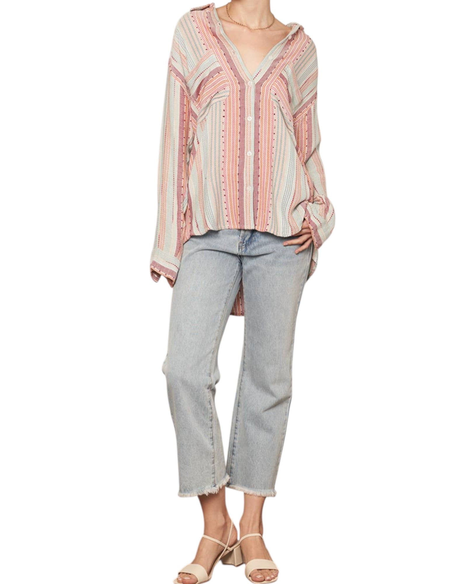 Person wearing a patterned blouse and light blue jeans on a white background
