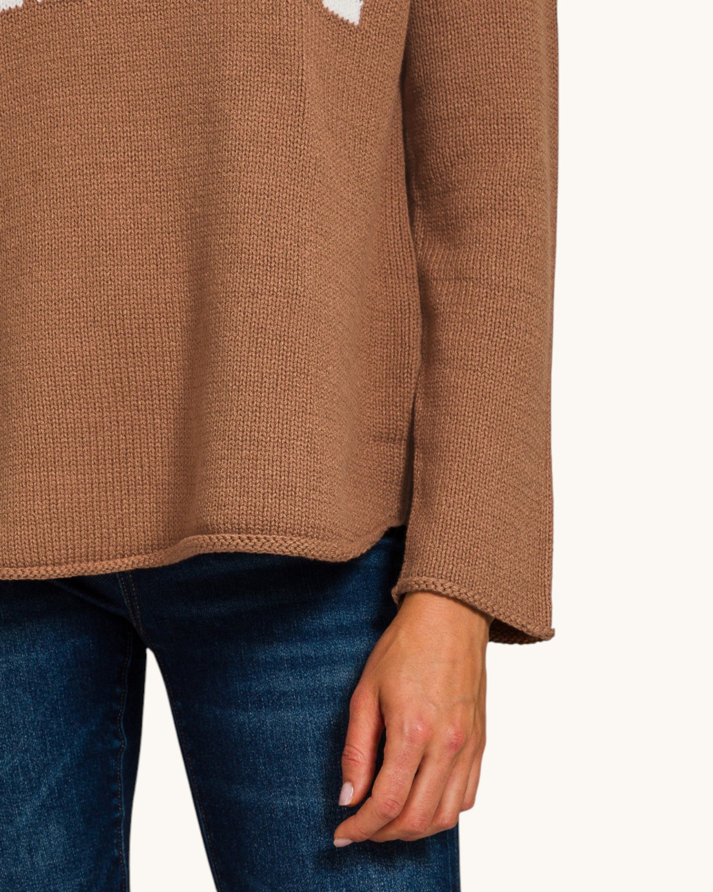 Brown sweater worn with blue jeans on a white background.