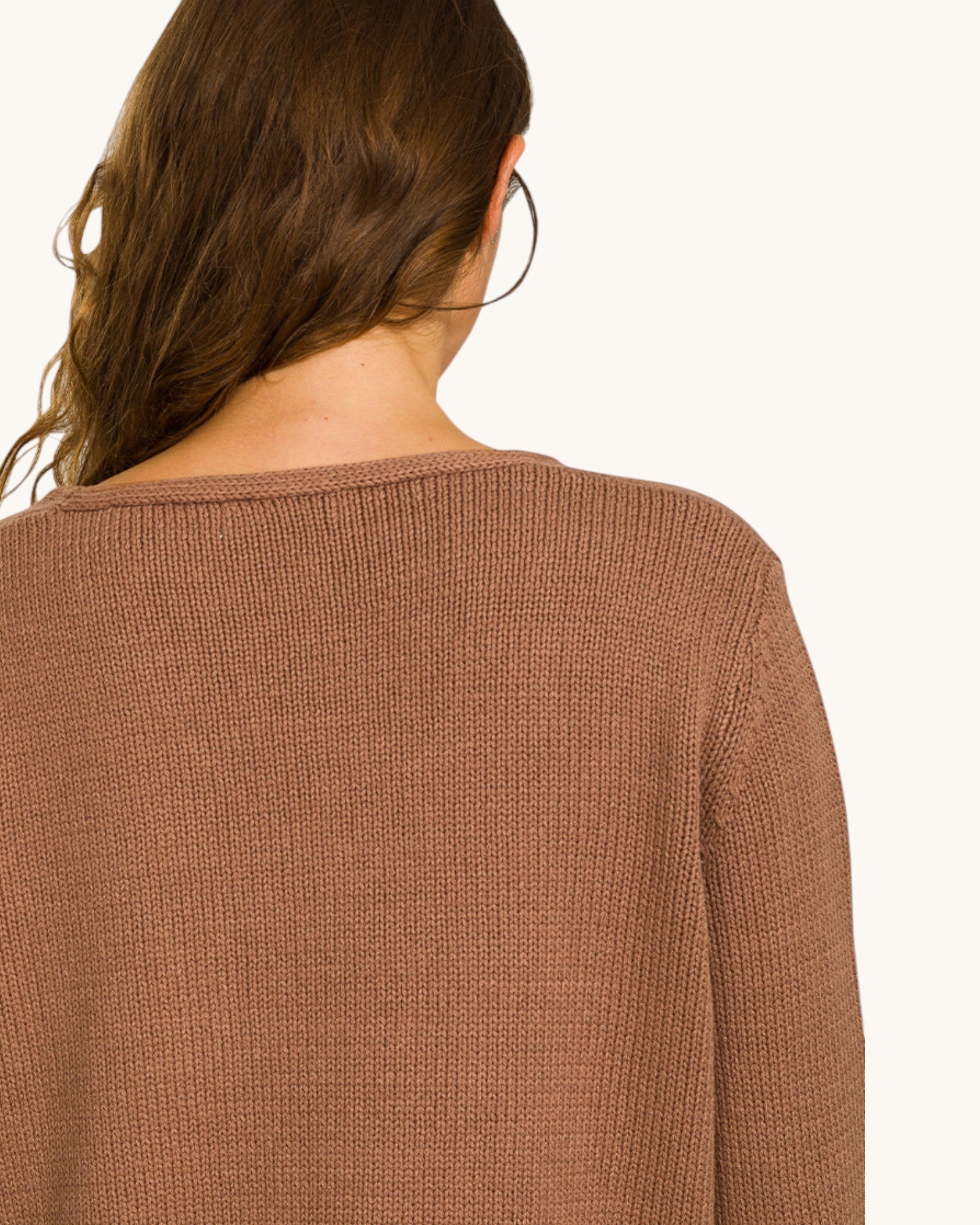 Brown sweater worn by a person on a white background.