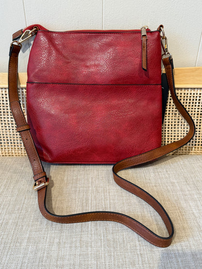 A burgundy leather shoulder crossbody bag with a brown leather strap and gold-tone hardware, displayed on a textured beige fabric surface.