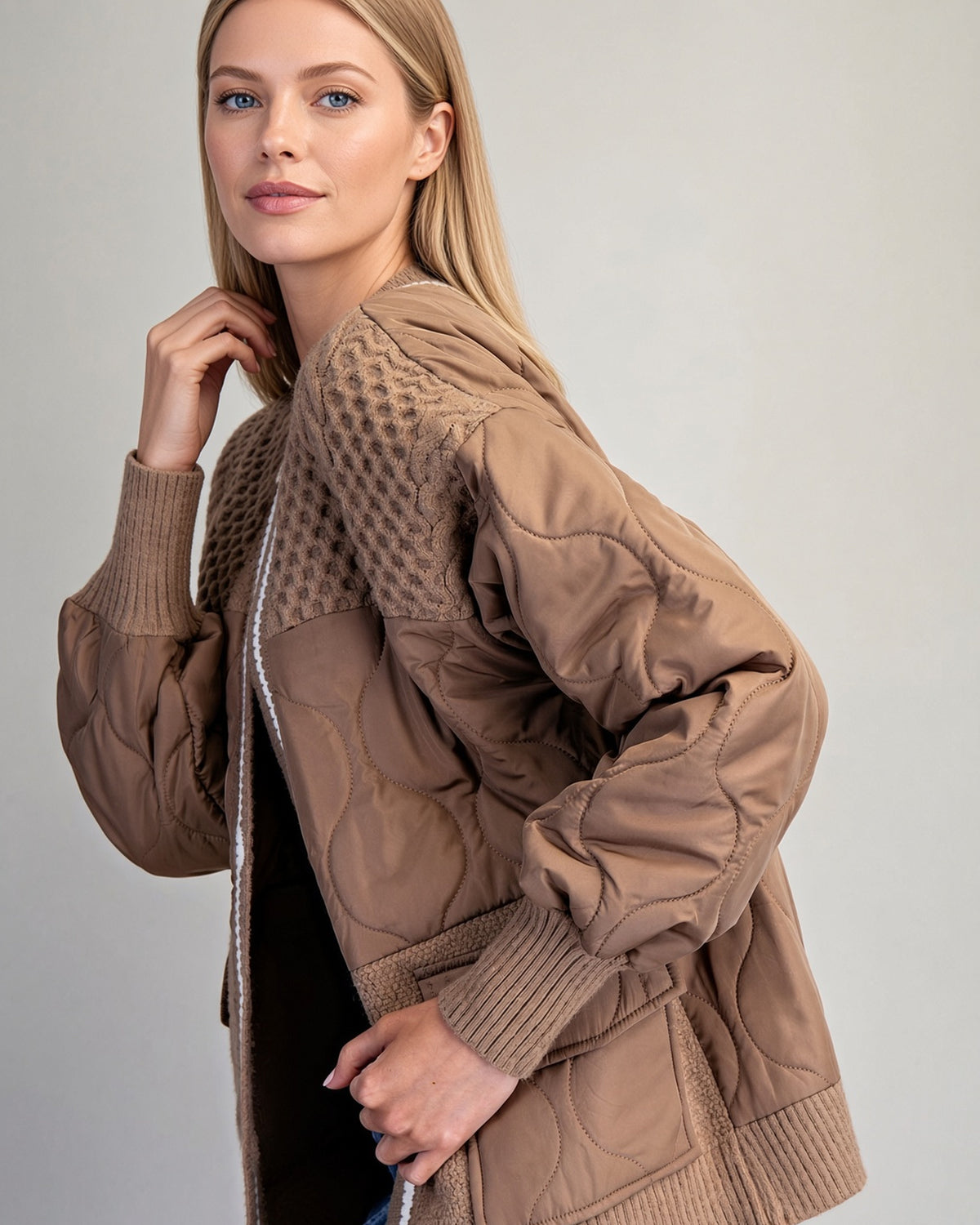Angled view detail of caramel mixed-media jacket showing curved quilt stitching across the shoulders and sleeves.