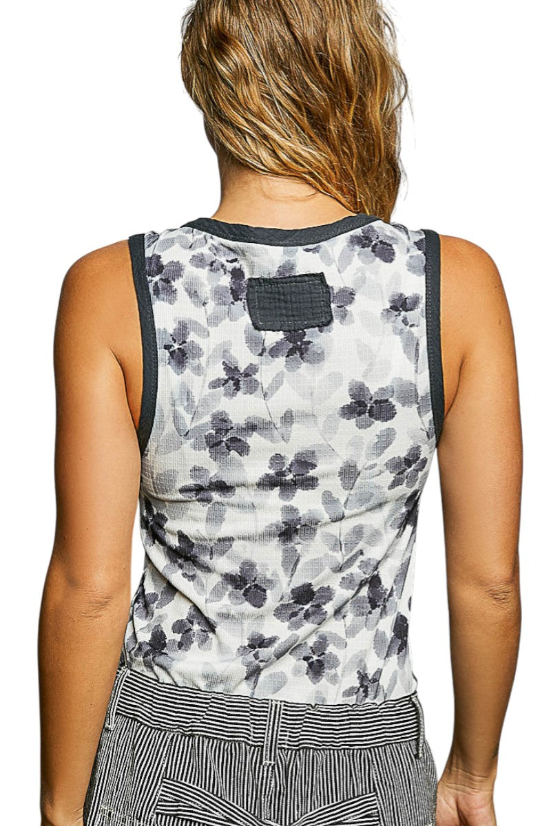 Person wearing a sleeveless floral top with a plain background.