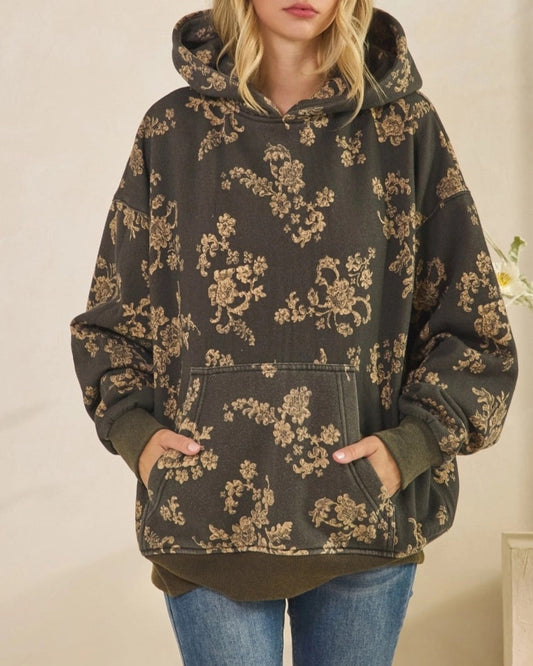 Woman wearing a floral-patterned hoodie and jeans against a neutral background
