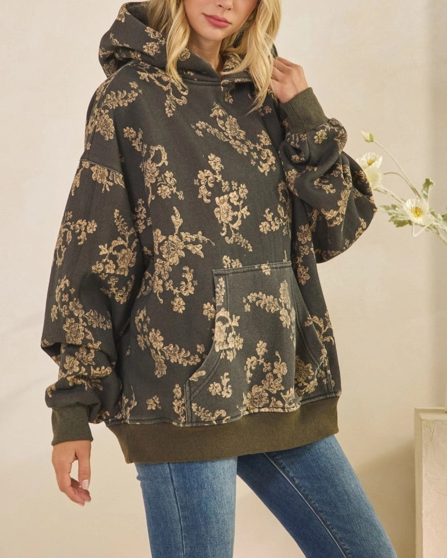 Woman wearing a floral-patterned hoodie and jeans indoors.