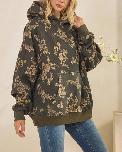Woman wearing a floral-patterned hoodie and jeans indoors.