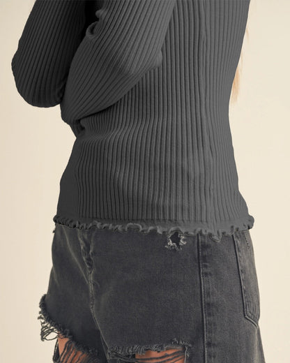 Bottom of a charcoal ribbed top and distressed black denim skirt on a beige background.