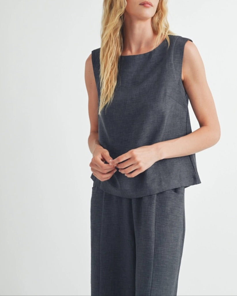 Woman wearing a dark gray sleeveless top against a white background.