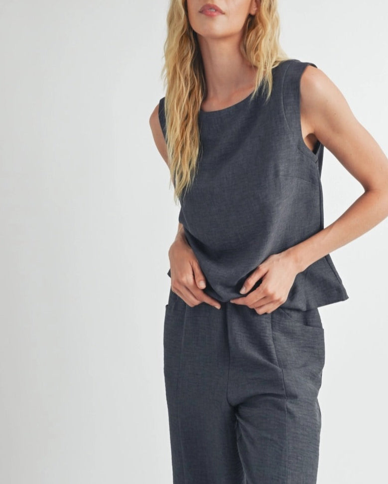 Woman wearing a dark gray sleeveless top and matching bottoms against a white background.