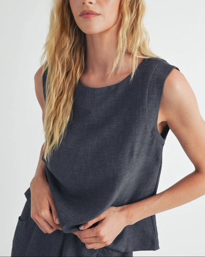 Woman wearing a dark gray sleeveless top against a white background.