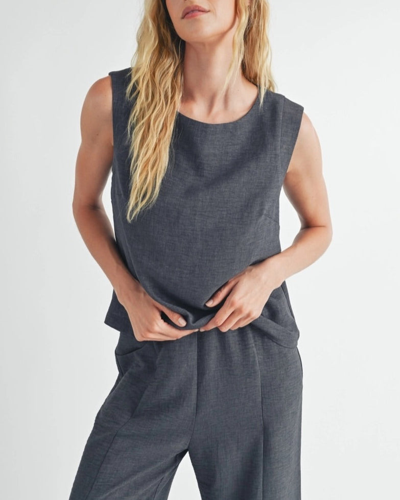 Woman wearing a dark gray sleeveless top against a white background.