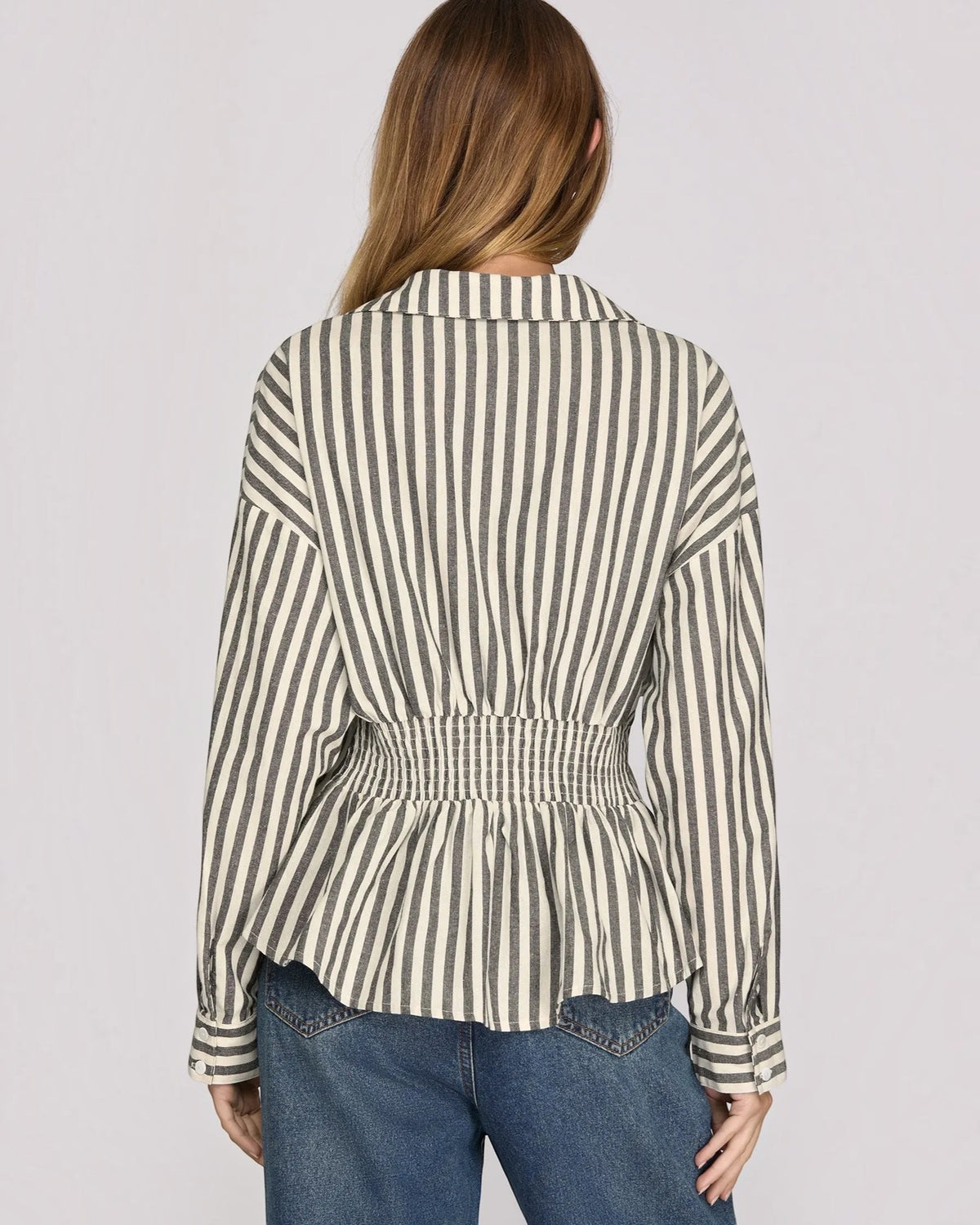 Back view of a model wearing a charcoal and white stripe button up with a smocked back. 