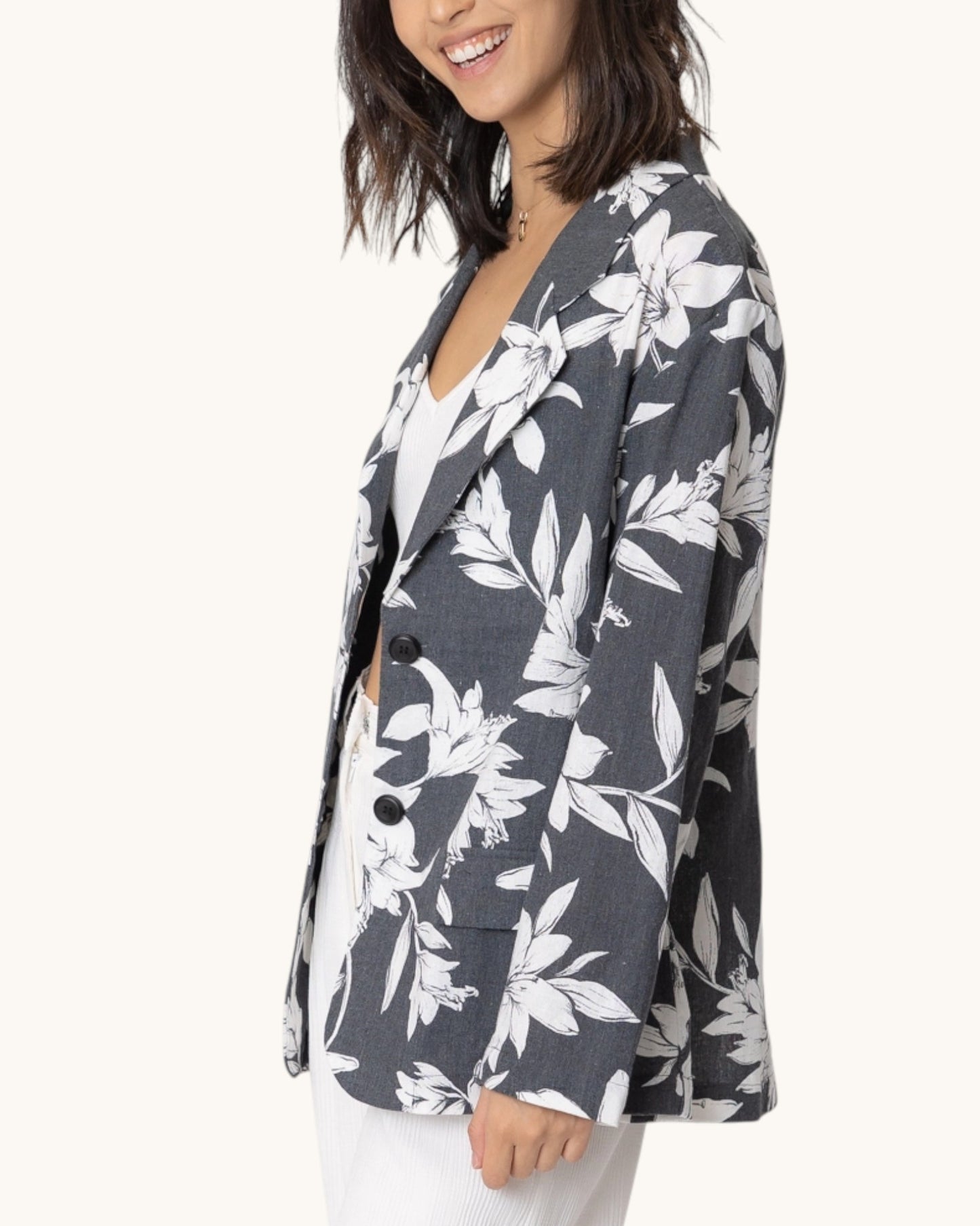 Side view of a woman wearing a floral blazer with a white background.