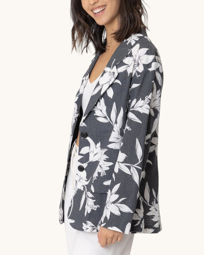 Side view of a woman wearing a floral blazer with a white background.