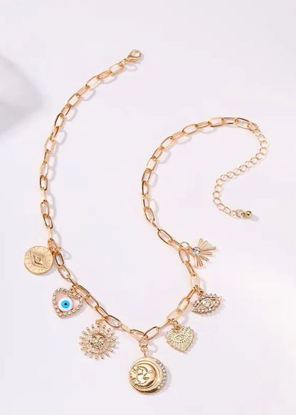 Gold-plated charm necklace with Sun, Evil Eye, Heart, and Hammered Disc charms, adjustable ball chain extension, and lobster clasp closure.