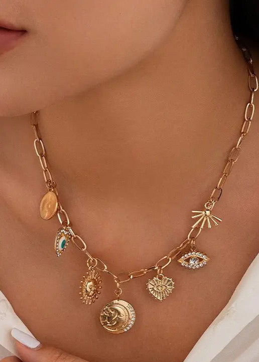Gold-plated charm necklace with Sun, Evil Eye, Heart, and Hammered Disc charms, adjustable ball chain extension, and lobster clasp closure.