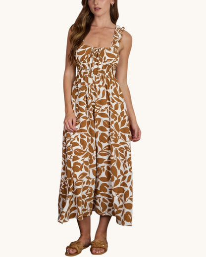 Woman wearing a warm brown and white leaf patterned summer dress on a white background.