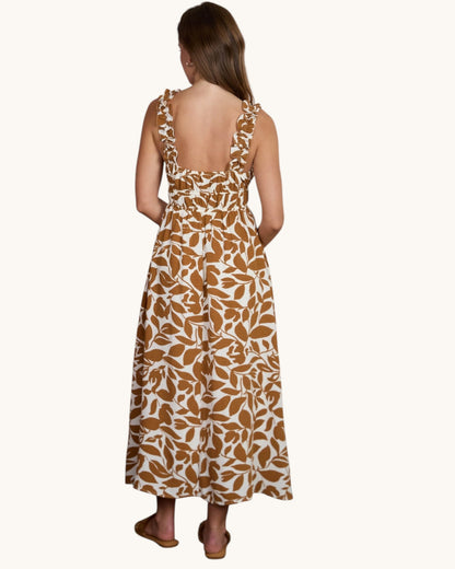 Back view of a woman wearing a long dress with a brown and white pattern on a white background.