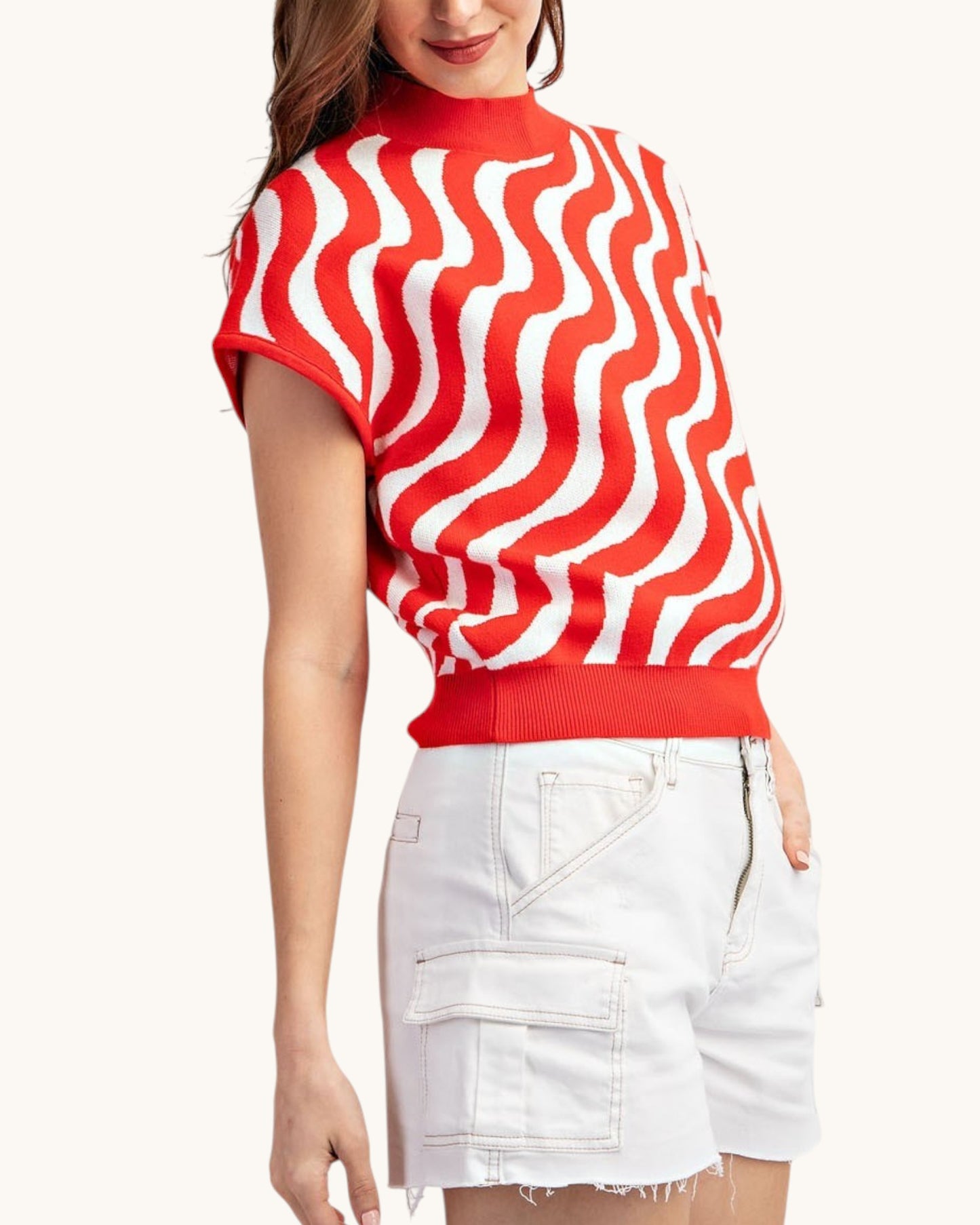Cherry red and white swirl short sleeve summer sweater worn with white shorts, side view.